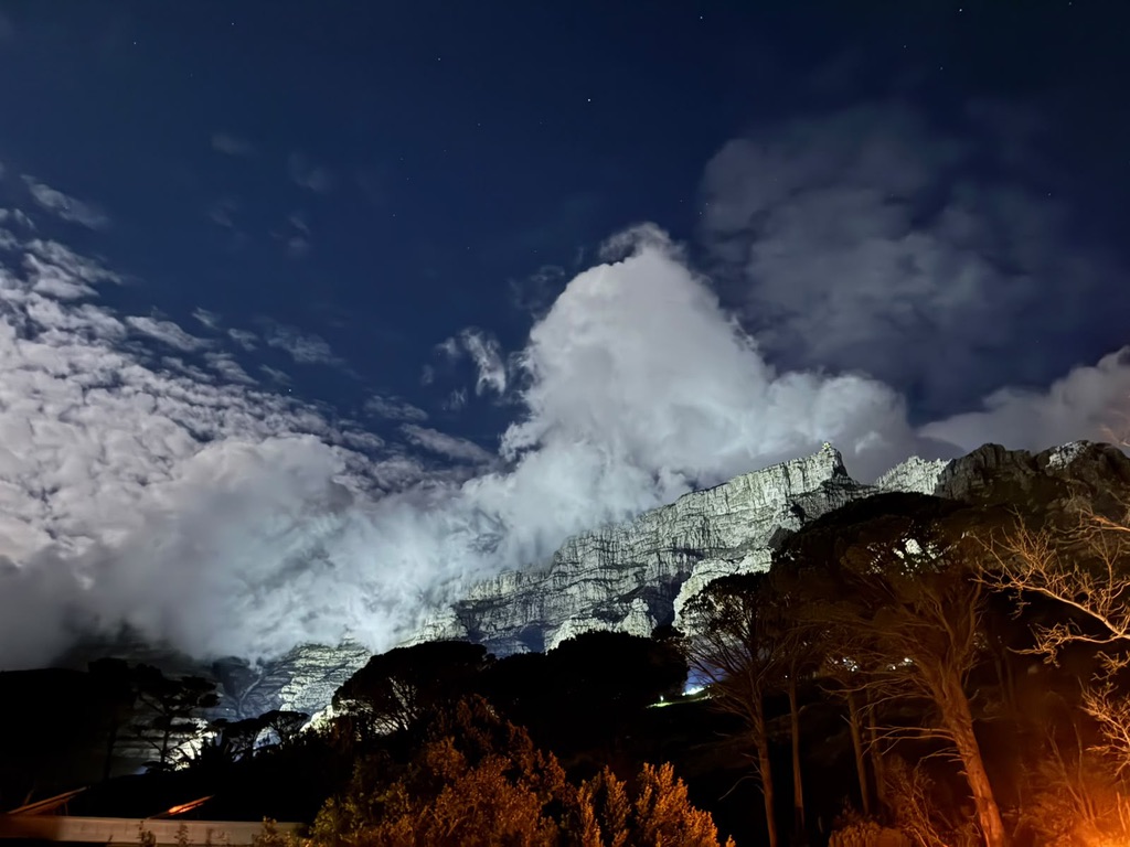 Table Mountain lit at night with cloud pouring over the ridge