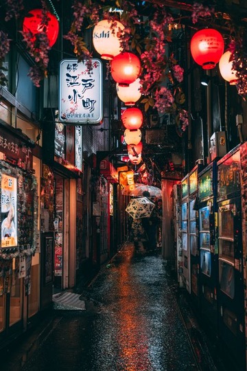 Narrow Tokyo alley lit by red lanterns with rain on the pavement