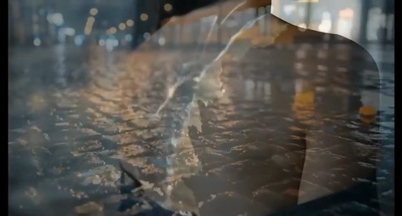 Blurred figure reflected over a rain-soaked city street at night